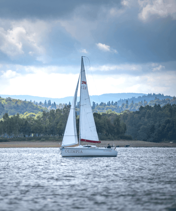 Sailboat on a lake with forested hills in the background