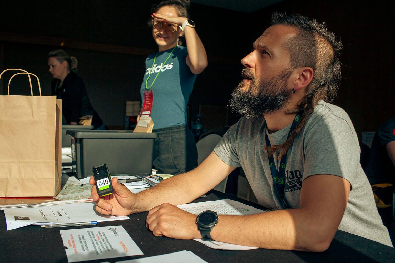 Event organizer holding a Poltrax GPS tracker at a race headquarters desk